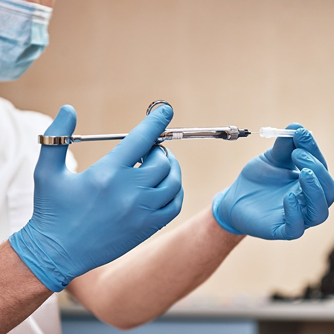 Oral surgeon filling local anesthesia syringe