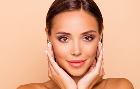 Woman with flawlessly smooth skin framing her face with her hands