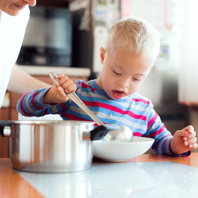 Child with dental problems from cleft lip and palate pouring soup in bowl