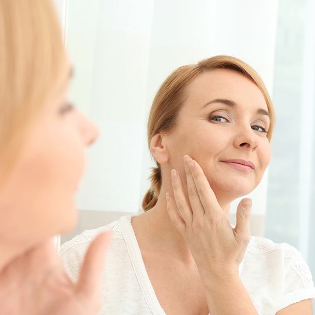 Woman examining her face after Radiesse treatment