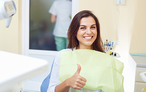 Smiling woman giving thumbs up in the dental chair