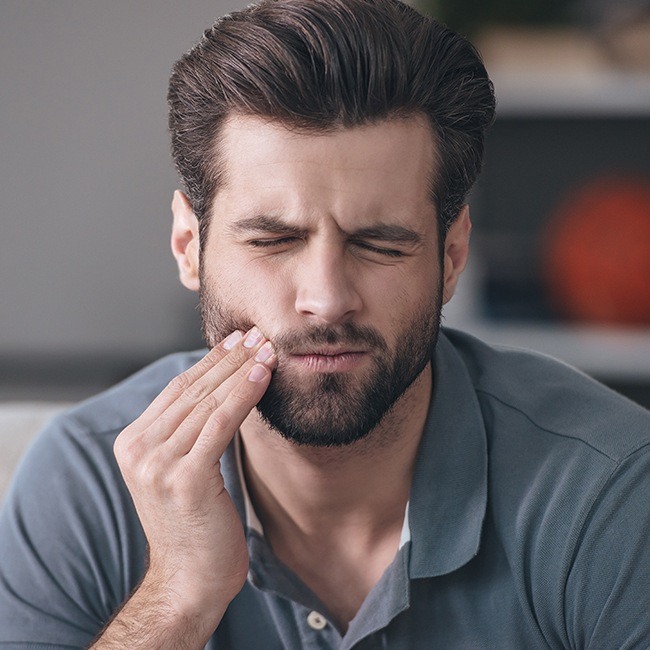 Man in need of dental emergency treating holding jaw