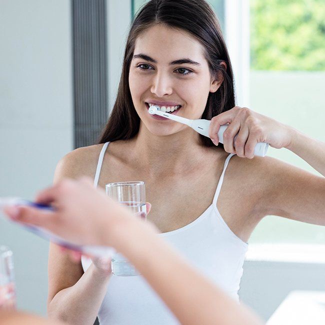 Woman brushing teeth to prevent dental emergencies