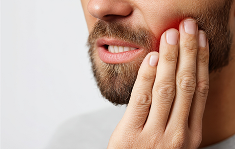 Close up of a man holding the side of his jaw in pain