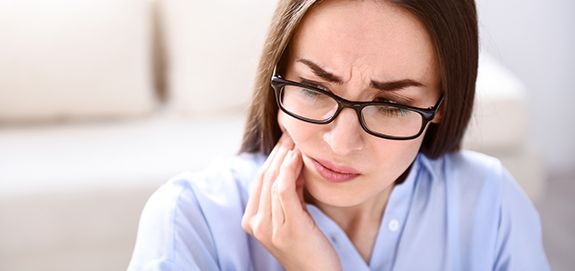 Woman in need of T M J treatment holding jaw