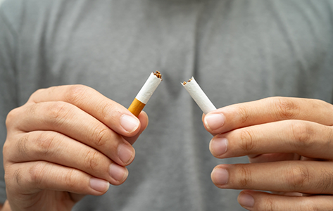 Person breaking a cigarette in half