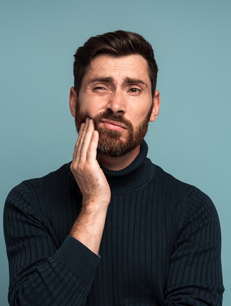 Man holding his cheek in pain before seeing an emergency dentist in Houston