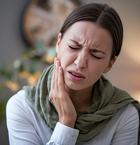 Woman wincing in pain and holding her cheek