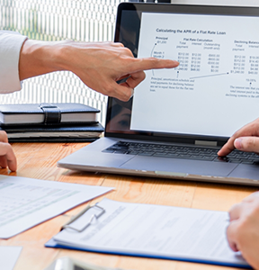 Two people at a table looking at charts on a computer
