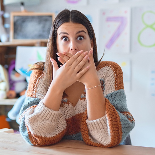 Woman with knocked out tooth covering her mouth