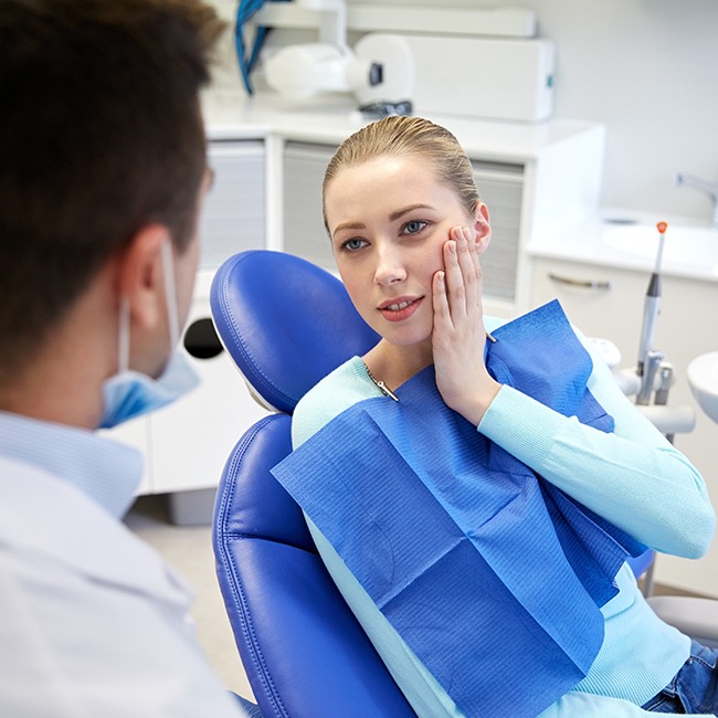 Woman in need of oral surgery holding jaw