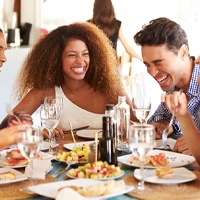 Happy friends with dental implants enjoying a meal together