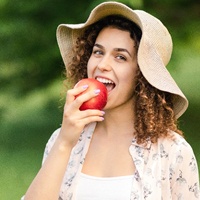 Woman biting into apple with help of her dental implants