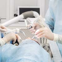 Dental implant surgical team carefully working on patient