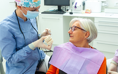 Dentist showing a model of implant dentures to a patient