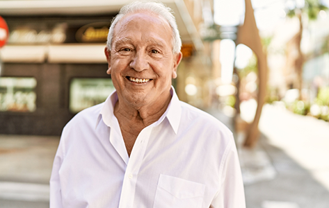 Smiling senior man in a pale pink buttoned shirt