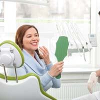Woman admiring her smile after receiving dental implant restorations