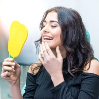 Happy patient admiring her new dental implant restorations