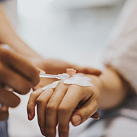 Oral surgery team member inserting IV into patient’s hand