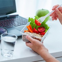Person enjoying healthy snack at desk in office
