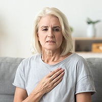 Older woman with hand over heart worries about oral cancer in Houston