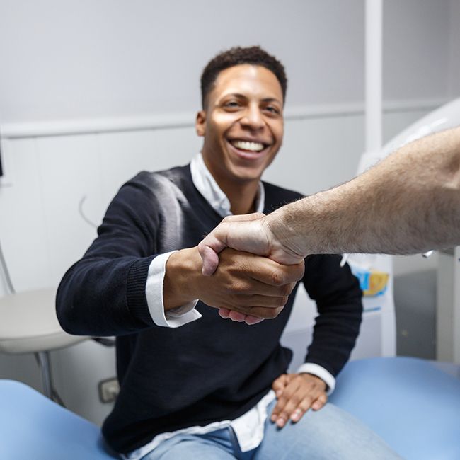 Patient shaking hands with oral surgeon after initial exam