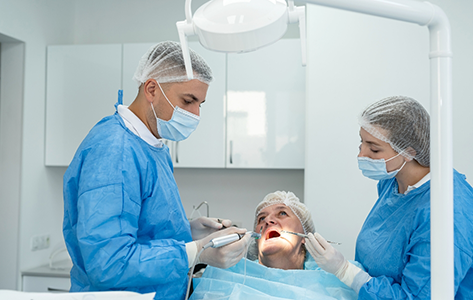 Woman having her mouth examined by two dental professionals
