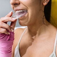 Woman placing mouthguard in her mouth
