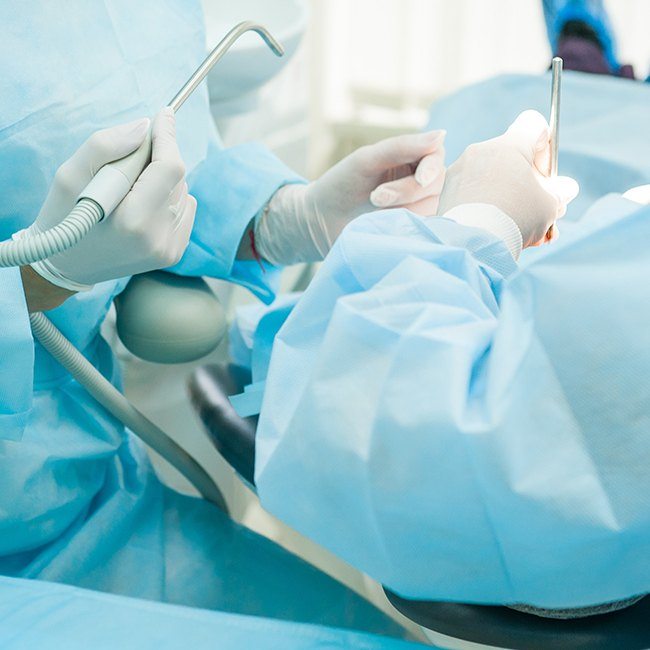 Two oral and maxillofacial surgeons treating a patient