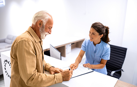 Senior man signing paperwork at a desk during a consultation