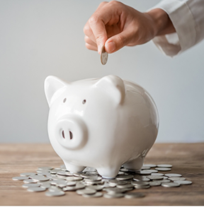 Hand putting coins into a piggy bank