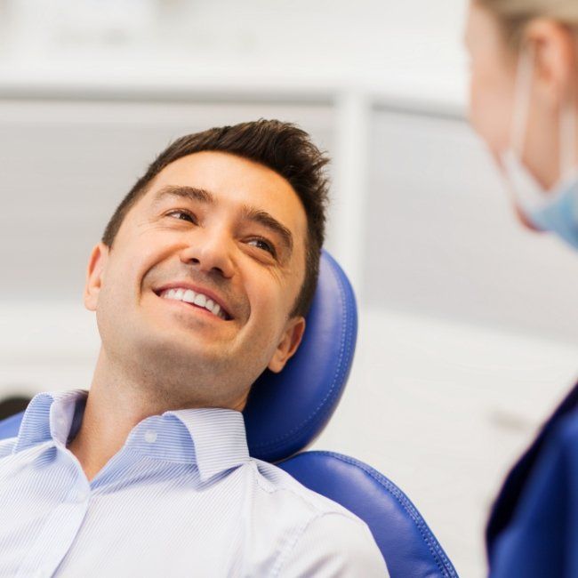 Smiling man talking to oral surgeon about wisdom tooth extraction