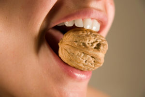Teeth biting down on walnut
