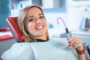 female patient at oral surgeon’s office holding suction tube