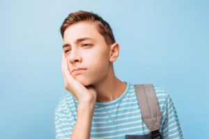 Teenage boy in striped shirt experiencing wisdom tooth pain