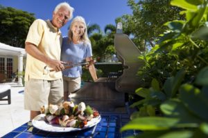 Senior couple with dental implants grilling summer foods