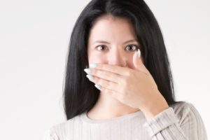 Woman covering mouth, wondering, “Do dental implants stain?”