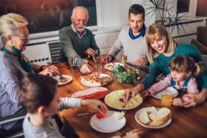 Older couple with dental implants enjoying a family dinner