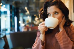 Woman sipping on coffee after healing from her tooth extraction