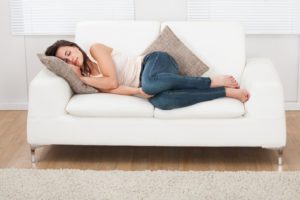 Woman on couch, sleeping after wisdom tooth extractions