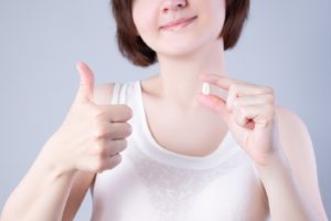 Woman holding tooth, enjoying benefits of tooth extraction