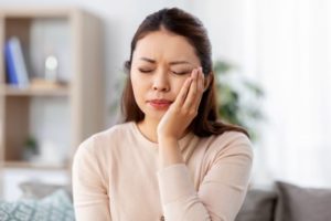 Woman with hand on face, suffering from a tooth infection