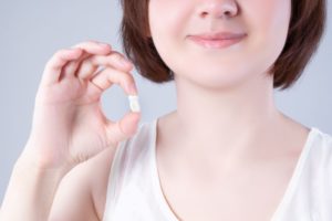 Woman smiling while holding extracted tooth