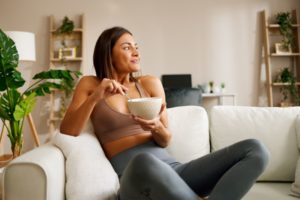 Woman sitting on sofa, holding a bowl and spoon