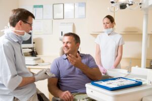 Middle-aged man talking with his dental care team 