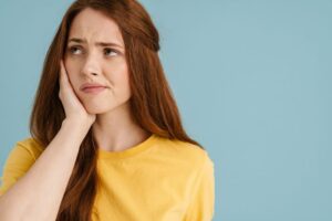 Young woman grimacing due to wisdom tooth pain 