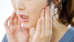 Concerned woman touching her jaw 
