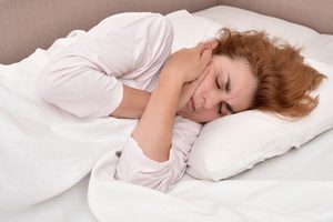 Woman experiencing jaw pain while lying in bed